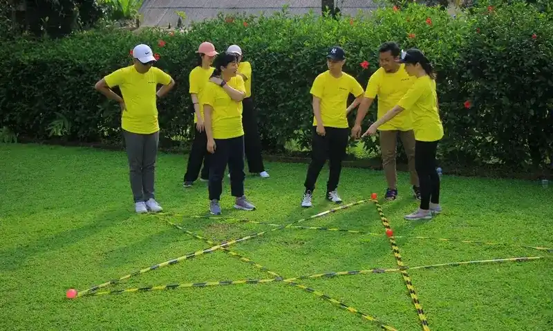 Peserta outbound sedang mengikuti simulasi kerjasama tim menggunakan media tali dan bola di lapangan rumput hijau bersama instruktur profesional Paintball Bogor.