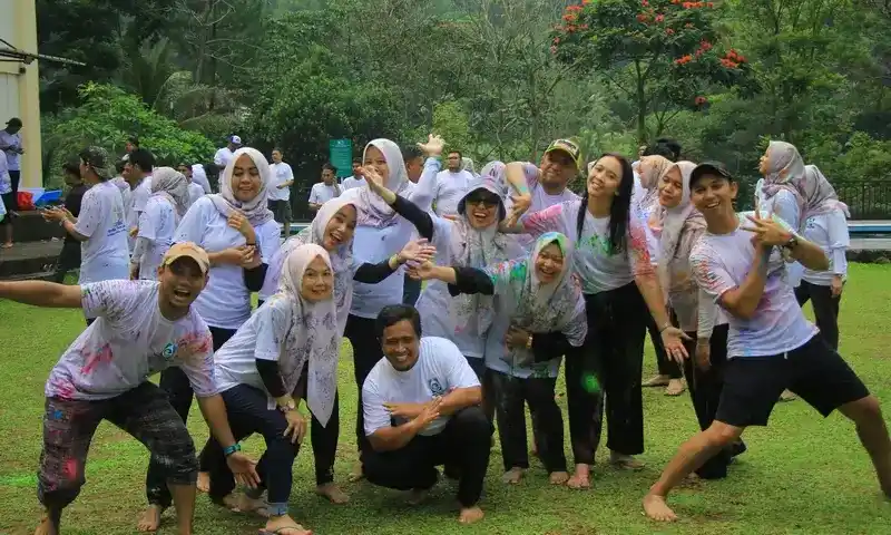 Potret peserta Paintball Bogor yang bahagia setelah menyelesaikan kegiatan outbound dan team building, menampilkan kebersamaan dan kegembiraan di lapangan rumput dengan latar belakang hutan.